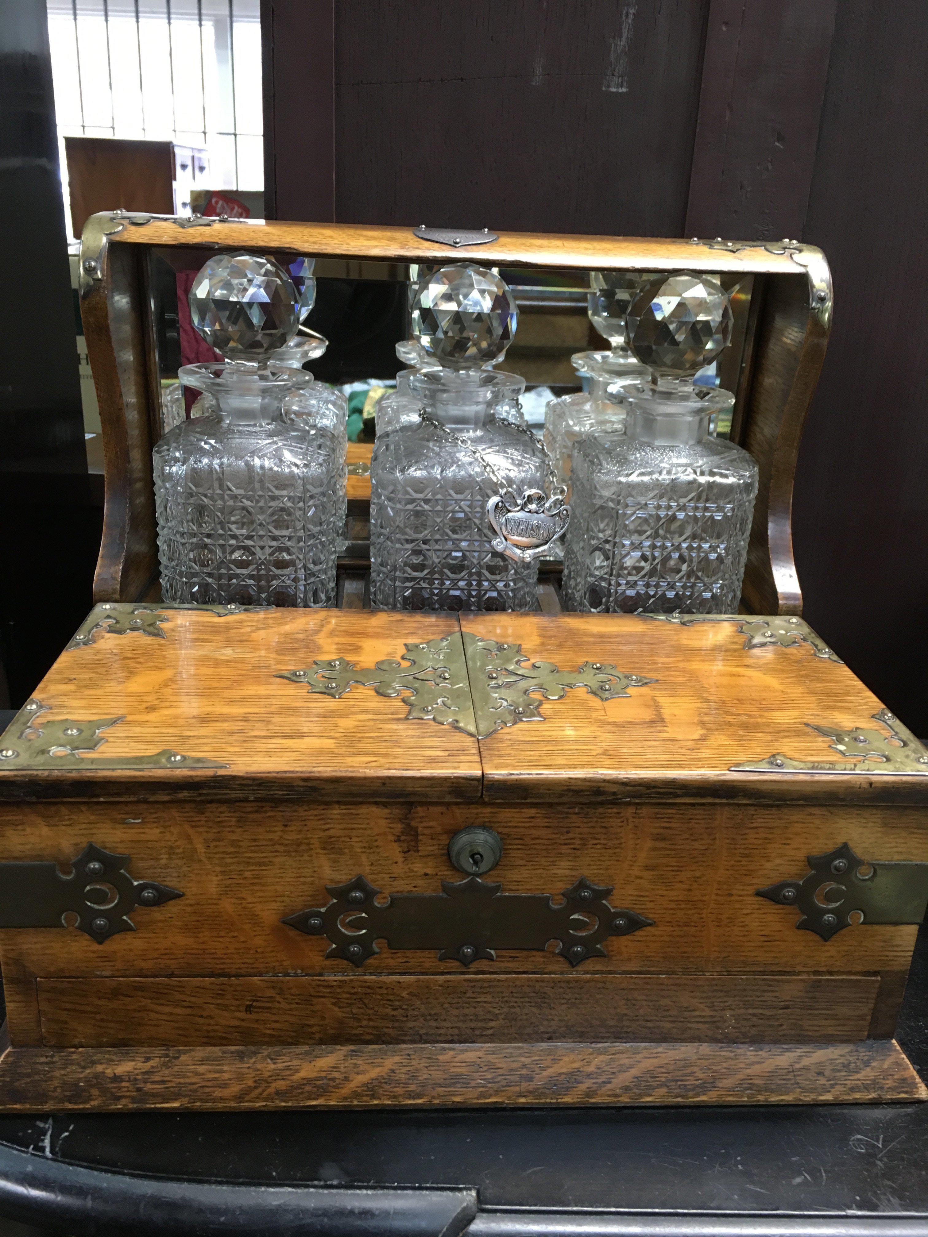 A oak tantalus with 3 glass decanters open section and a single drawer