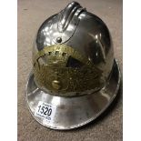 A vintage French firemans helmet with brass badge inscribed Saprurs, Pompiers, De ales Pins silver