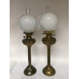 A pair of brass oil lamps with clouded shades, height approx 72cm.