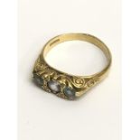 A 22ct gold ring set with three pale blue stones.A