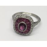 A platinum Art Deco style ruby and diamond ring. Central oval-cut ruby surrounded by a Hal of