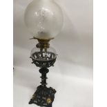 A Victorian oil lamp with gothic influences with glass shade and chimney.