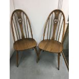 A set of four Ercol dining chairs .