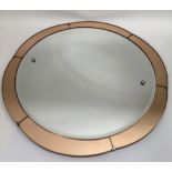 A circular Art Deco mirror with peach colour surround