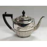 A silver teapot with half gadrooned decoration, Sh