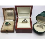 Three silver rings in boxes, one with a jade type