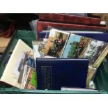 A box containing a collection of postcards and stamps in binders on various subjects including