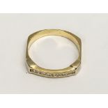 An 18ct gold ring of unusual square shape, set with a band of small diamonds.Approx 2.7g, N