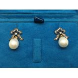 A pair of white pearl drop earrings with diamond bow tops, boxed