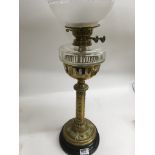 A Victorian brass oil lamp with gothic influence with shade a chimney.