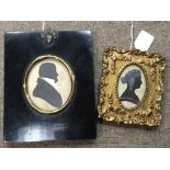 A silhouette of a Georgian gentleman in black frame and a silhouette of a Victorian lady in a