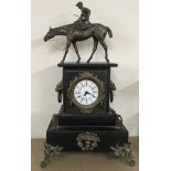 A black slate mantle clock having gilt mounts, lion handles and ceramic dial mounted with a jockey