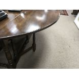 A Large oak drop leaf table the twin flap top above turned columns united by stretchers , 160 by