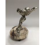 A chrome car mascot , the spirit of ecstasy, raised on a circular marble base, approx height 19.