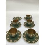 A set of five Royal Worcester, green ground coffee cups and saucers painted with flowers and gilded