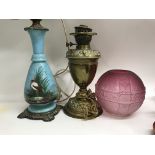 Two Victorian oil lamps and a cranberry glass shade .