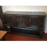 A Jacobean style oak sideboard the rectangular top above three cupboards the central door with