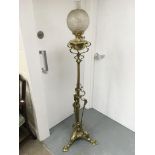A freestanding brass oil lamp with a clear glass shade, approx height 157cm.