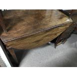 A Georgian mahogany drop leaf table with fluted legs .