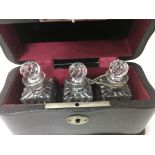 A glass decanter with silver collar and three glass perfume bottles in a fitted case ,
