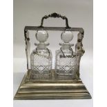 A two bottle tantalus with spirits labels in silver plated stand