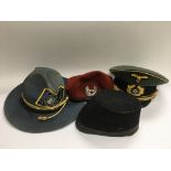 Four hats comprising a vintage GPO cap, a reproduction Nazi officer's hat and two others.