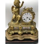 A gilt ormolu French mantle clock the enamel dial with Roman numerals flanked by a cherub inset with