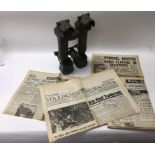A pair of trench binocular periscopes marked 1954 alongside WW2 newspaper clippings including the