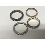 Four eternity rings inset with CZ or white sapphire stones. (4)