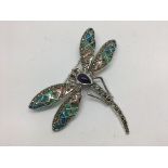 A silver dragonfly brooch set with large cabochon