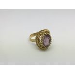 An 18ct gold ring set with an amethyst type stone,