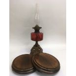 A cranberry glass oil lamp and two wooden stands