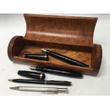 A burr wood box with two Parker fountain pens, one silver pencil and one other pen