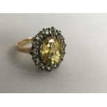 An 18ct gold ring set with a citrine in diamond su