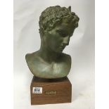 A painted plaster bust of "Boy of Marathon" on a wooden plinth.