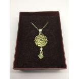 A silver and peridot pendant on a silver chain.