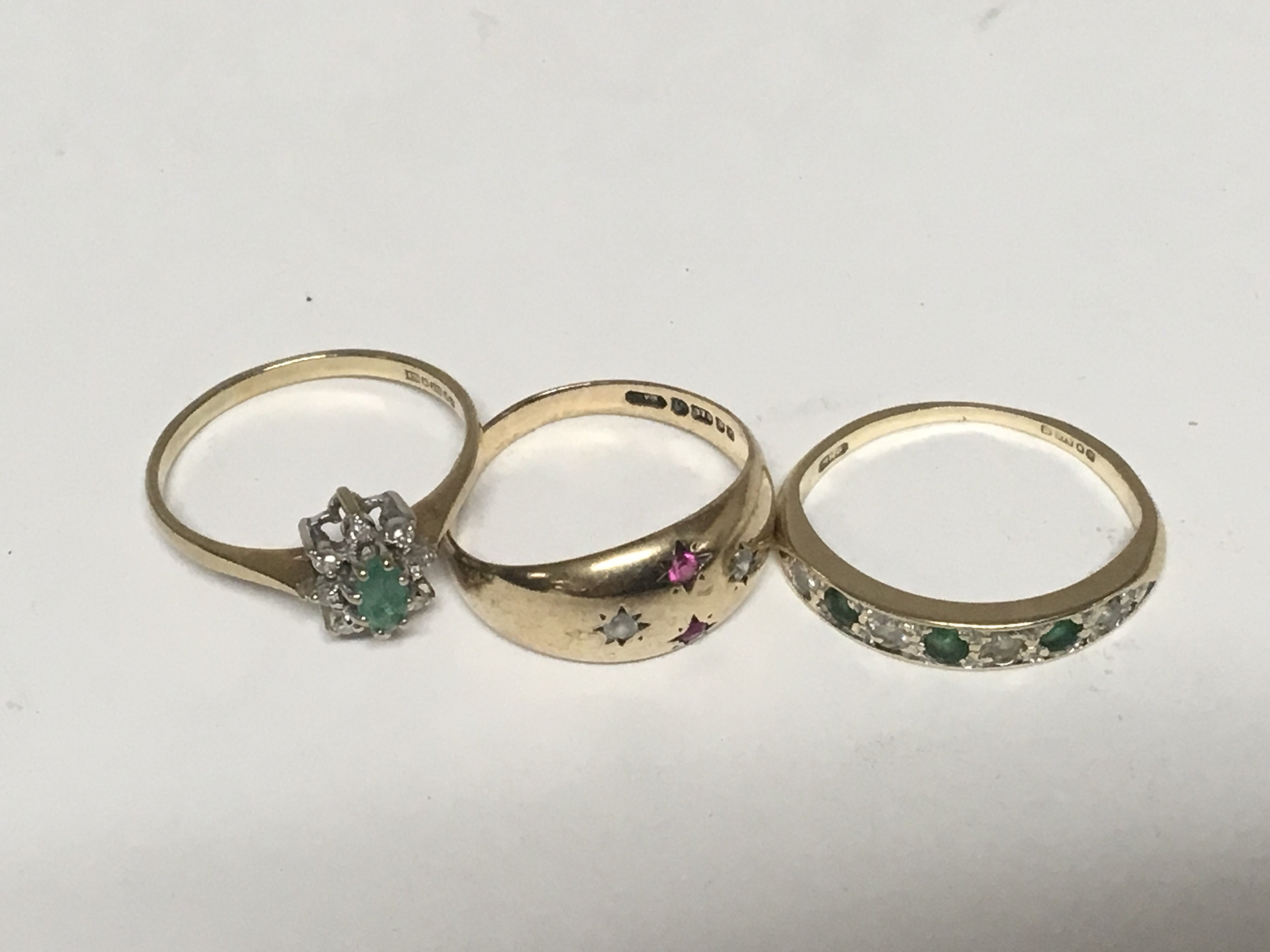 Three gold rings set with Emeralds Diamonds and Ru