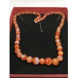 A cornelian bead necklace with round and facet cut beads and having a 9ct gold clasp.