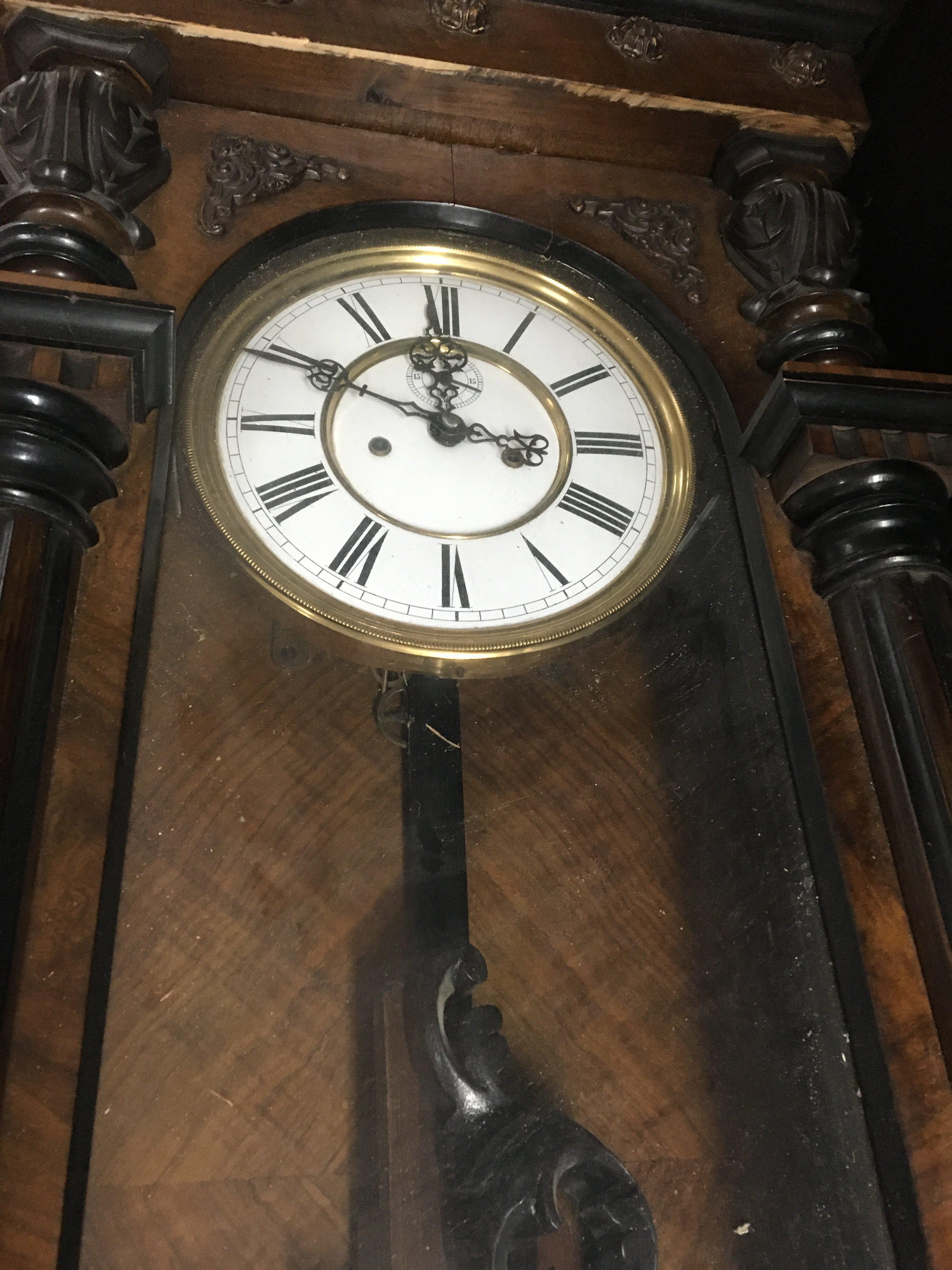 A walnut Vienna wall clock with Roman numerals and visible pendulum