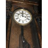 A walnut Vienna wall clock with Roman numerals and visible pendulum