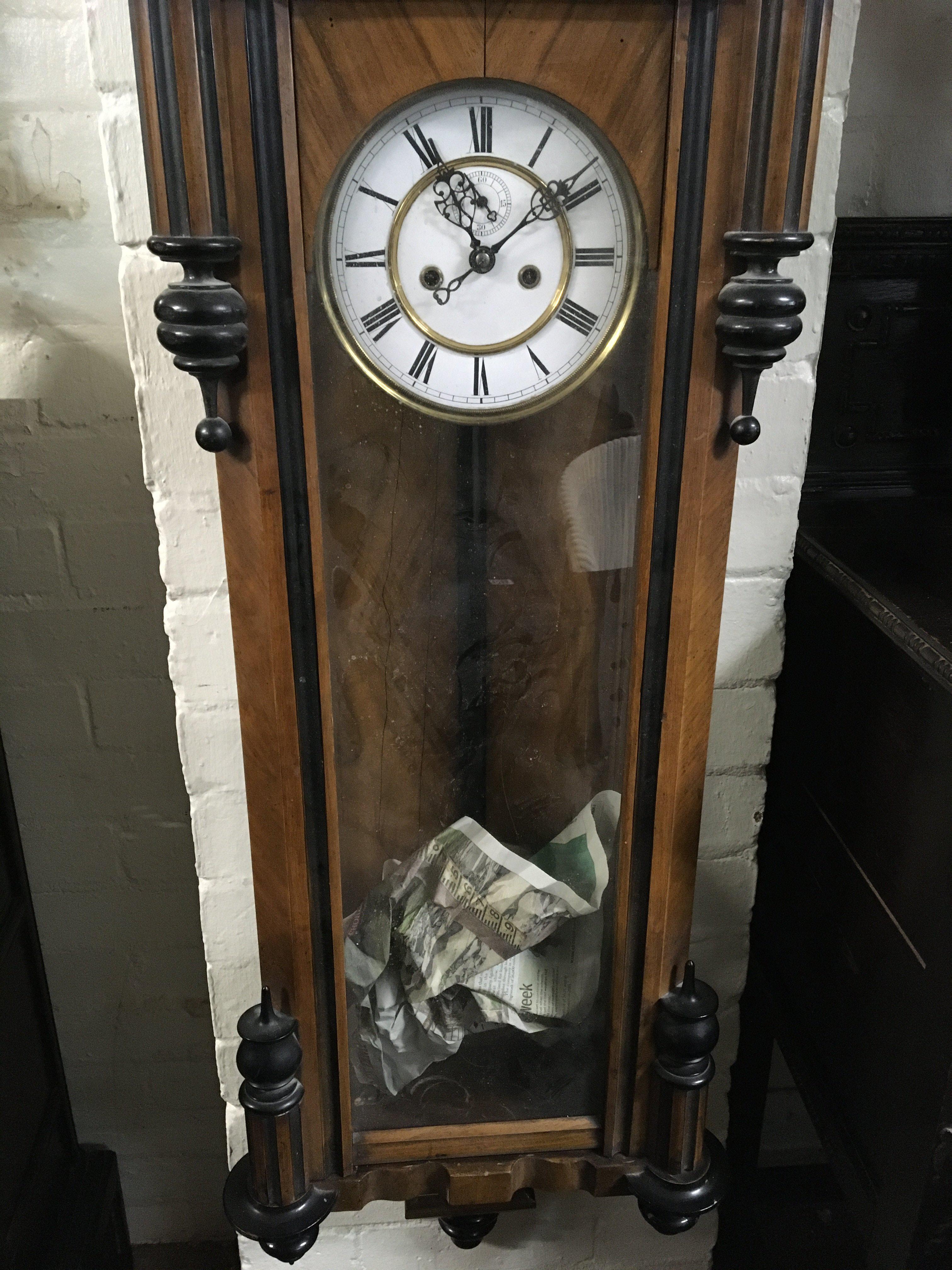 A walnut Vienna wall clock the enamel dial with Roman numerals and and visible pendulum.