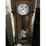 A walnut Vienna wall clock the enamel dial with Roman numerals and and visible pendulum.