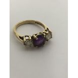 A 9ct gold ring set with an amethyst flanked by wh