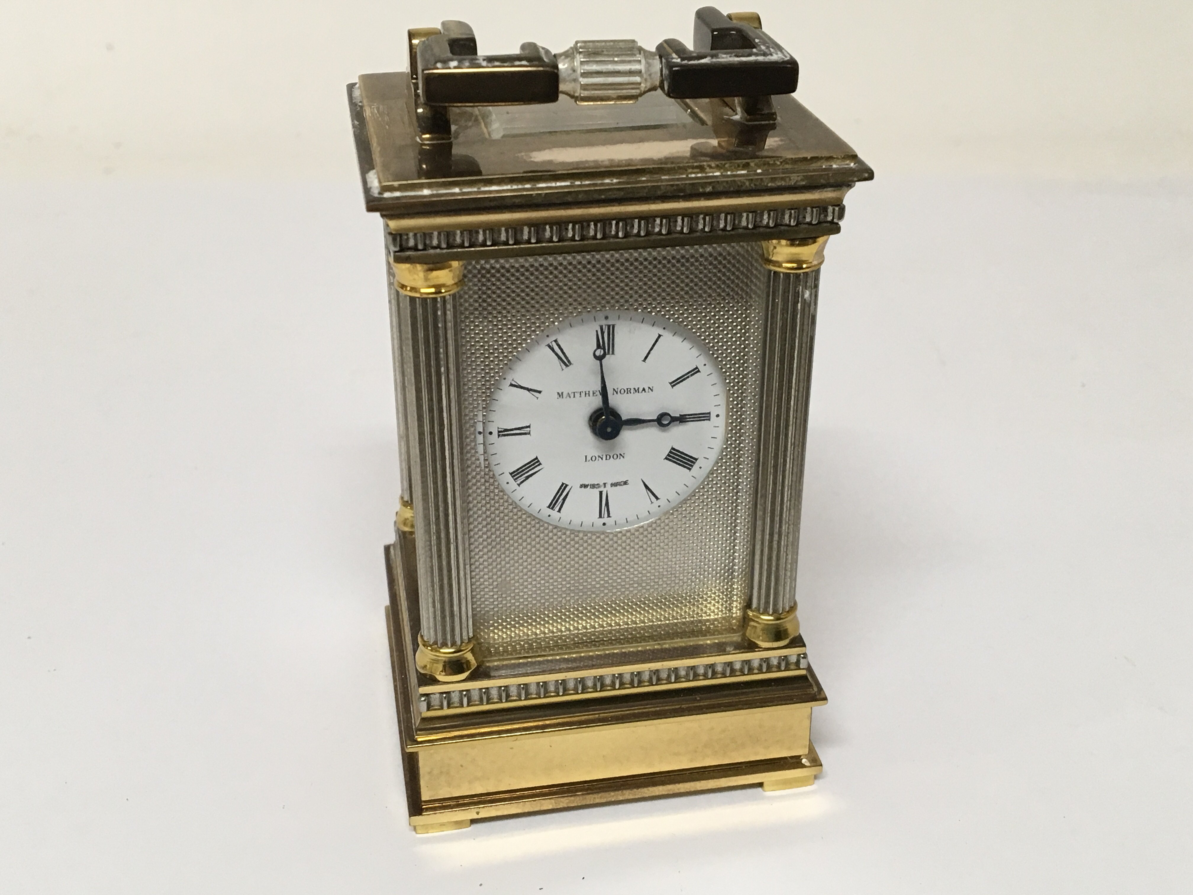 A miniature brass carriage clock with pillars to each corner the dial with Mathew Norman London
