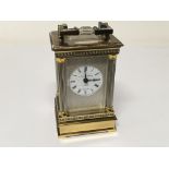 A miniature brass carriage clock with pillars to each corner the dial with Mathew Norman London