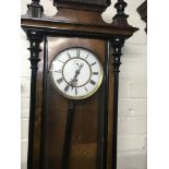 A Vienna walnut wall clock the enamel dial with Roman numerals and visible pendulum.