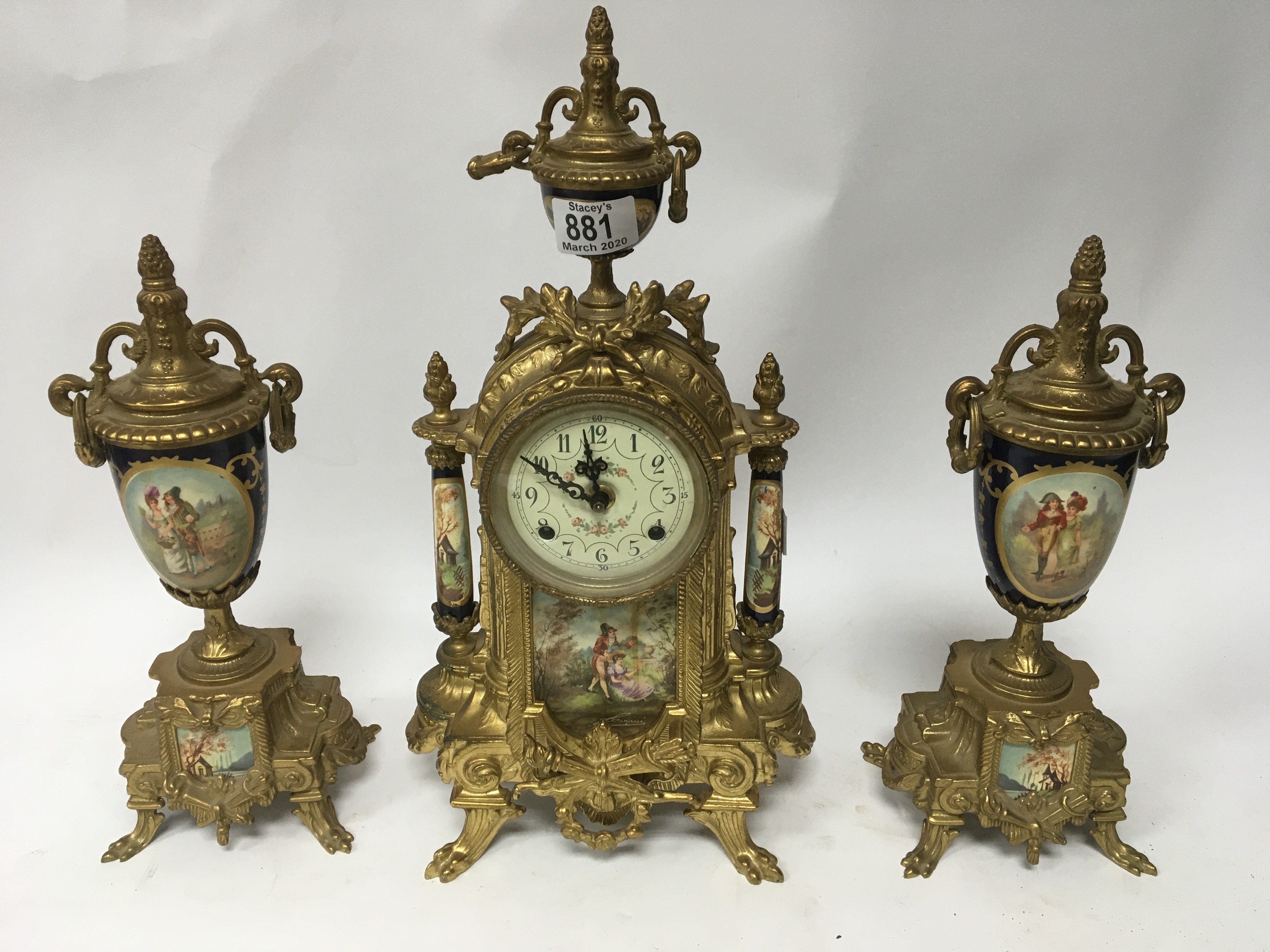 A gilt brass serves style porcelain clock garniture.