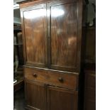 A mahogany linen cupboard with a pair of doors dra