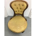 A Victorian walnut nursing chair with button back on cabriole legs .