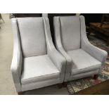 A pair of modern arm chairs upholstered in a light grey fabric.